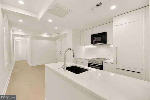 a kitchen with stainless steel appliances granite countertop a sink and a stove top oven with wooden floor