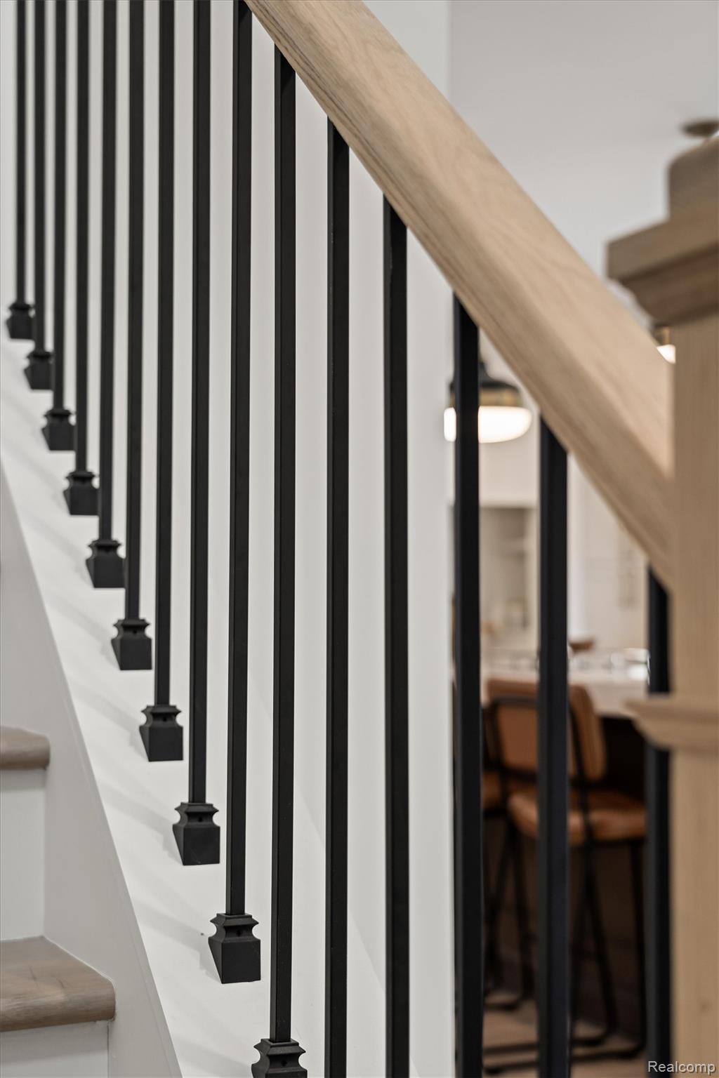 347 Highland Avenue Rochester, MI 48307 - Photo 20 of 59 Staircase featuring a natural wood handrail, black iron balusters, and light-toned wood-finish treads