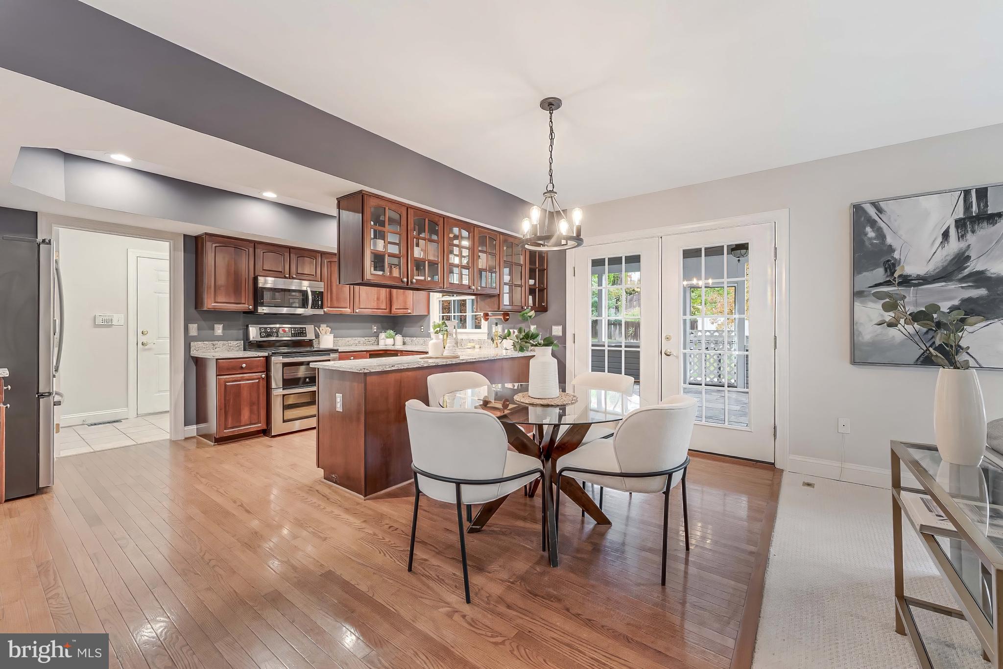 8926 Jameson Street Lorton, VA 22079 - Photo 11 of 32 a dining room with stainless steel appliances kitchen island granite countertop a table chairs and a refrigerator