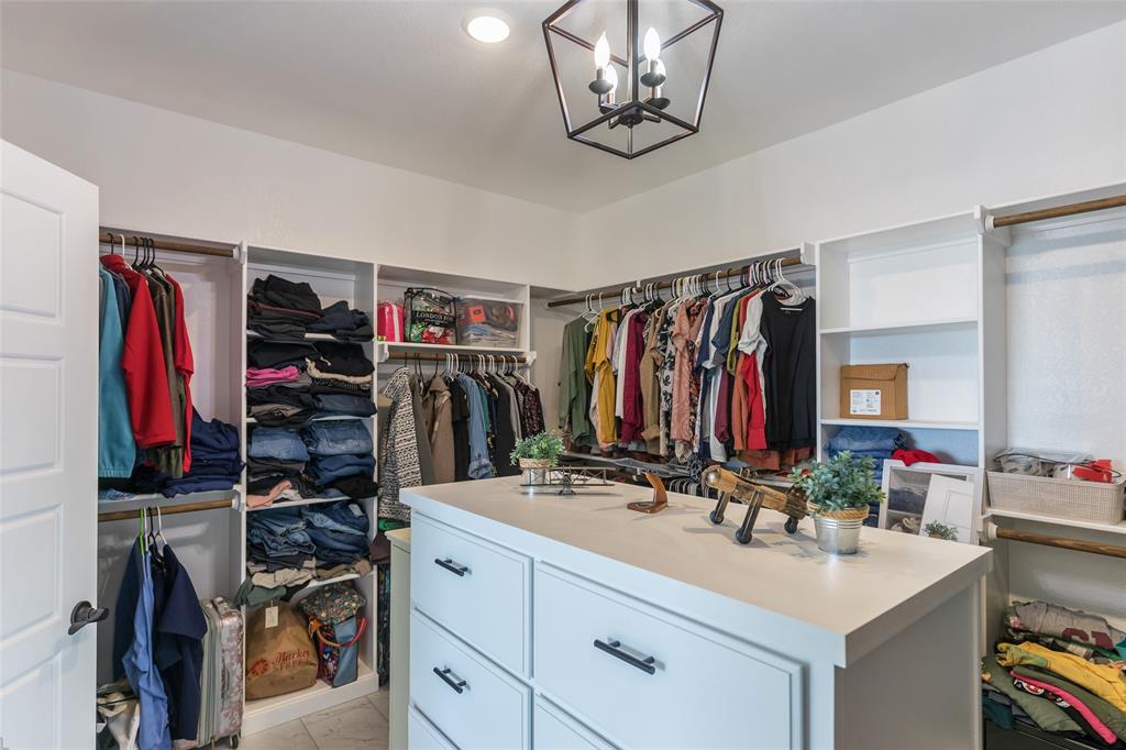 107 Kleingrass Road Abilene, TX 79606 - Photo 19 of 33 Expansive closet featuring an island with built-in drawers, extensive hanging rods, multiple shelving units, and a contemporary ceiling light fixture