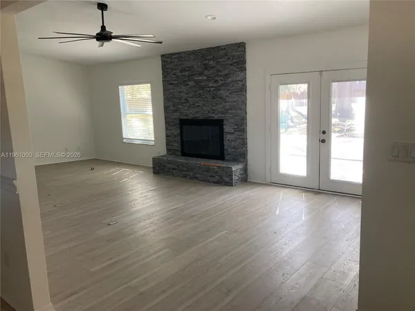an empty room with wooden floor fireplace and windows