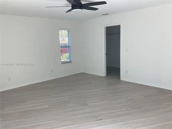an empty room with wooden floor and window