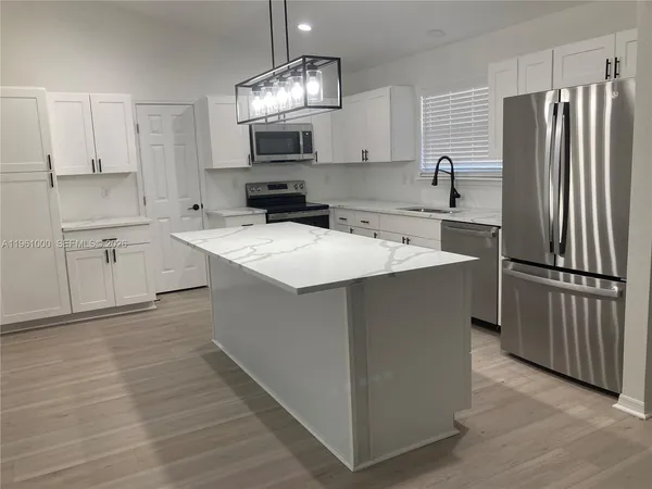 a kitchen with stainless steel appliances a sink stove refrigerator and cabinets