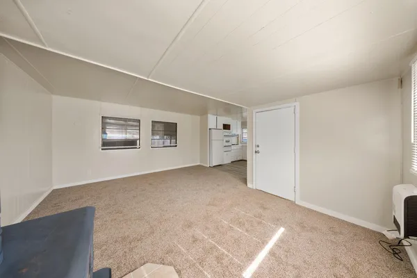 an empty room with chandelier fan and windows
