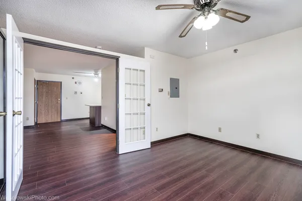 an empty room with wooden floor and ceiling fan