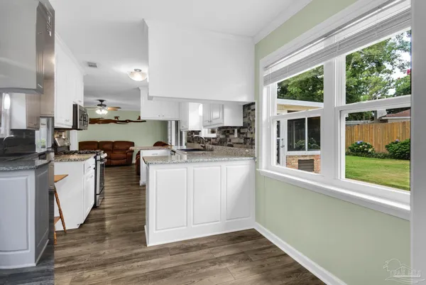 a kitchen with white cabinets and wooden floor