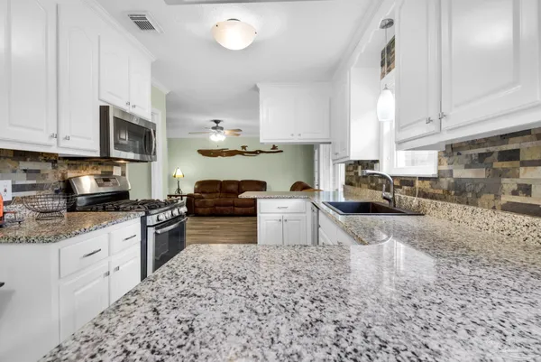 a kitchen with granite countertop a stove sink microwave and cabinets