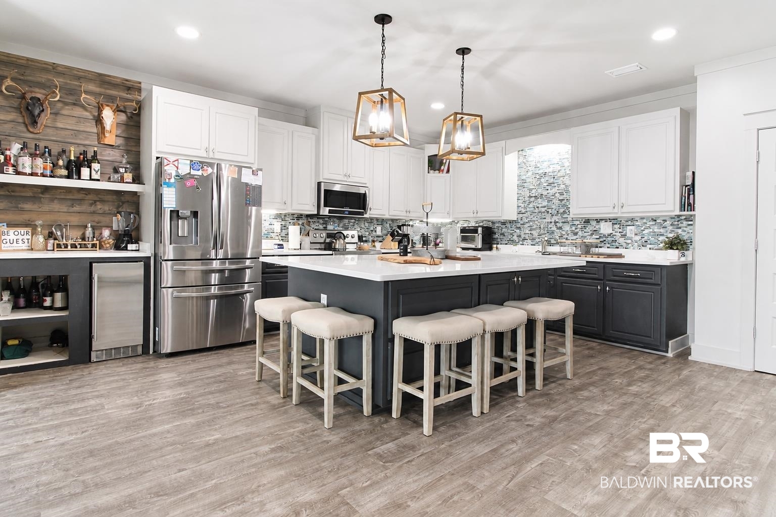 9825 Wolf Creek Ridge Elberta, AL 36530 - Photo 31 of 76 Spacious kitchen featuring a large central island with seating, a mosaic tile backsplash, wood-finish flooring, white upper cabinetry, and dark lower cabinetry