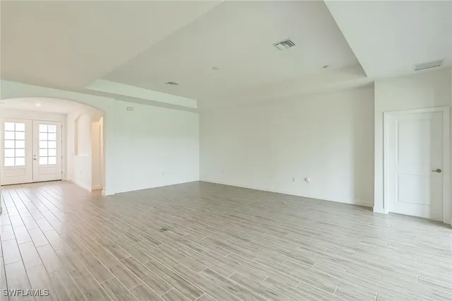 a view of an empty room with wooden floor and windows