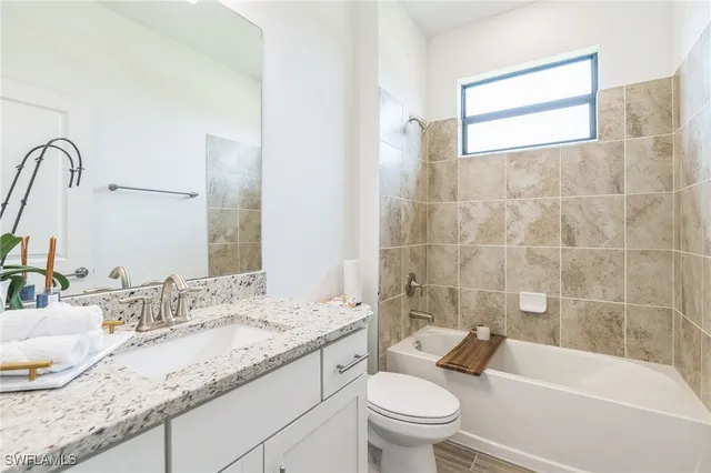 a bathroom with a granite countertop toilet a sink and bathtub