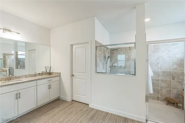 a spacious bathroom with a granite countertop sink a mirror and a shower