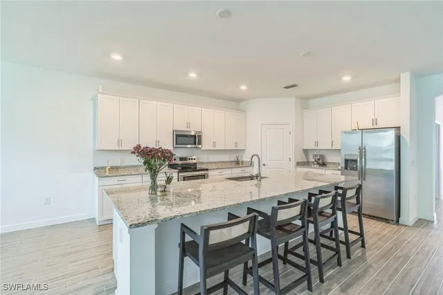 a kitchen with stainless steel appliances granite countertop a table chairs sink refrigerator and microwave