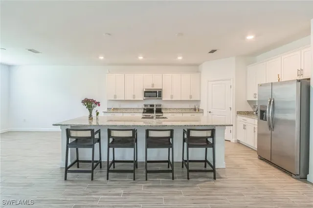 a kitchen with granite countertop a table chairs stove microwave and cabinets
