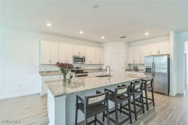 a kitchen with stainless steel appliances granite countertop a table chairs sink refrigerator and microwave