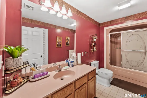 a bathroom with a granite countertop sink vanity mirror and toilet