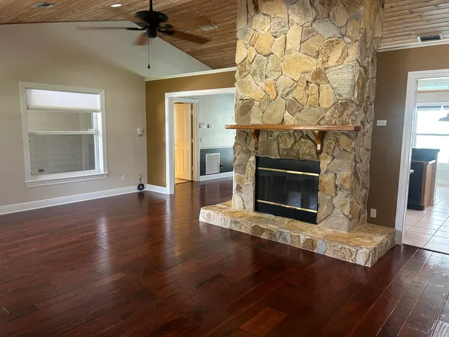 an empty room with wooden floor a fireplace and a window