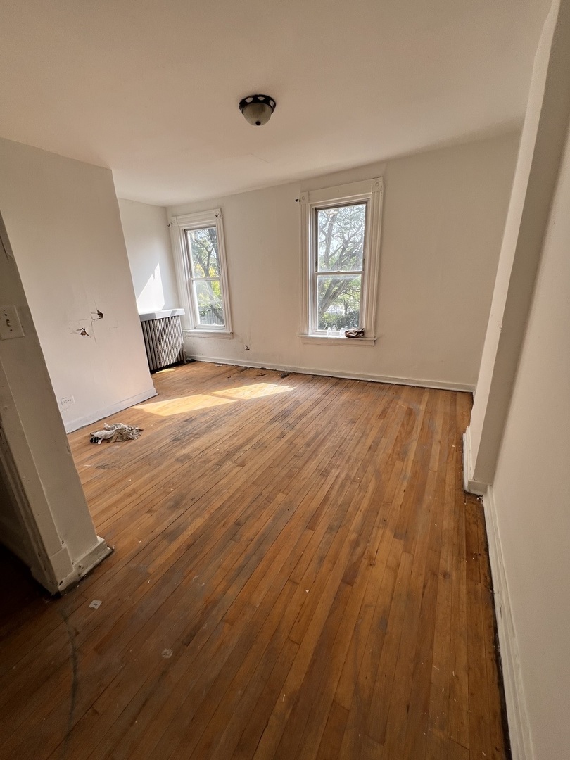 10614 South Langley Avenue, Unit 10614 Chicago, IL 60628 - Photo 3 of 11 wooden floor in an empty room with a window
