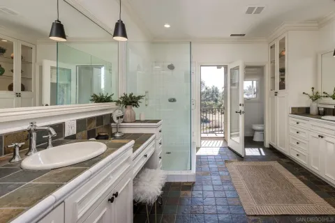 a bathroom with a granite countertop sink a mirror a bathtub and shower