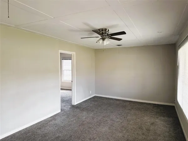 an empty room with a window and a ceiling fan