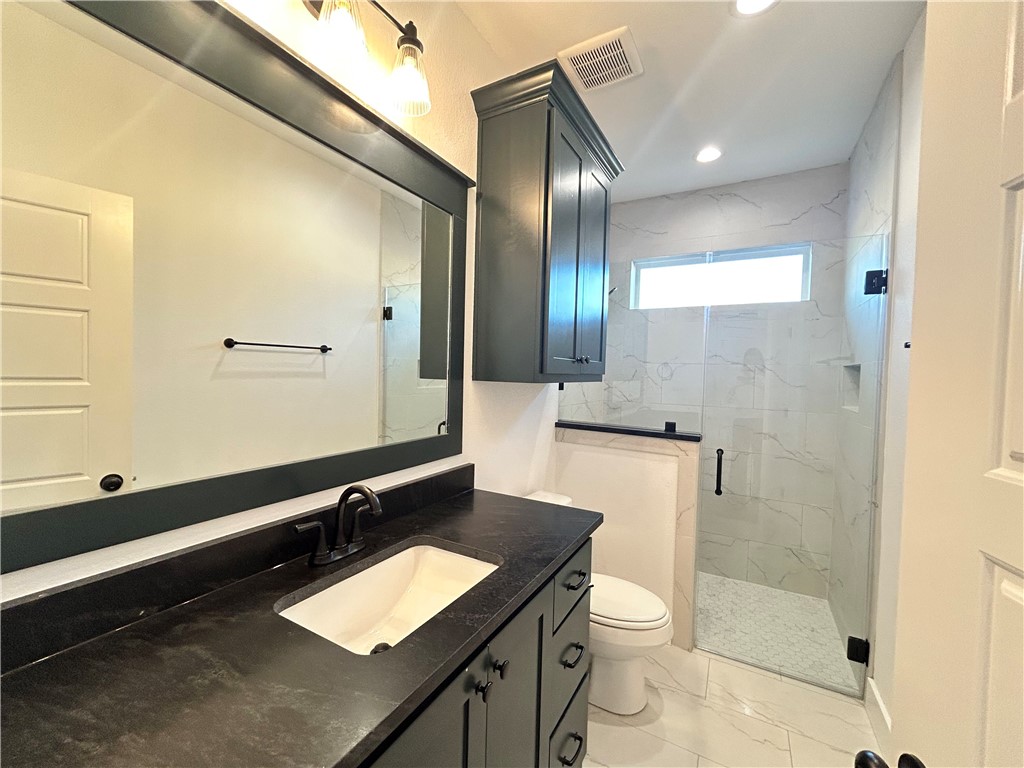 4015 Pacific Crest Way Bryan, TX 77802 - Photo 13 of 22 a bathroom with a granite countertop sink toilet a mirror and shower