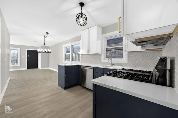 a kitchen with kitchen island stainless steel appliances a sink cabinets and wooden floor