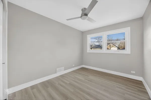 an empty room with wooden floor and ceiling fan
