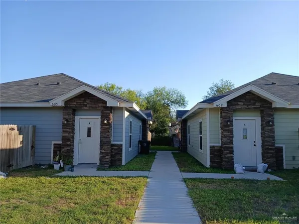 a front view of house with yard and trees in the background