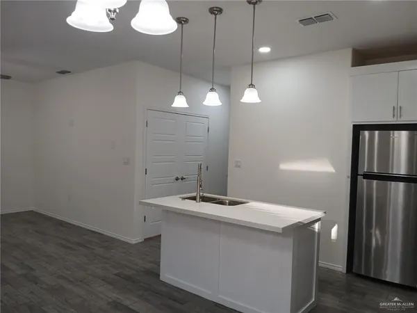 a kitchen with a sink a refrigerator and chandelier