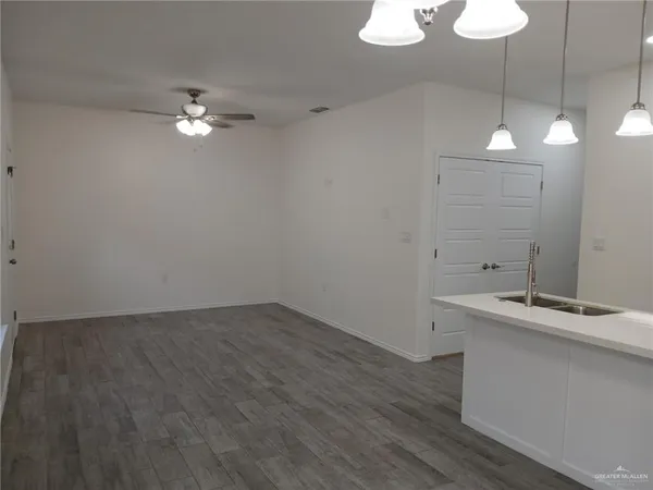 a view of a room with a chandelier fan and wooden floor