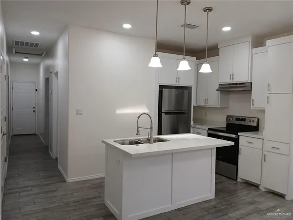 a kitchen with kitchen island a sink stainless steel appliances and wooden floor