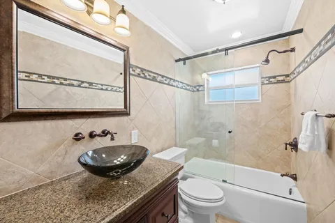 a bathroom with a granite countertop sink mirror toilet and bathtub