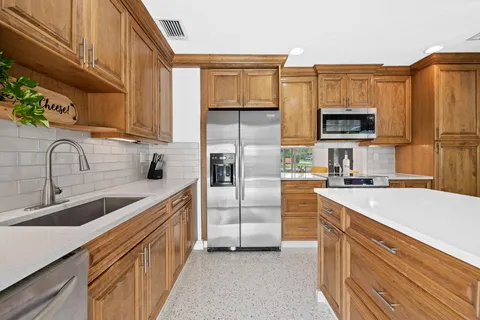a kitchen with stainless steel appliances granite countertop a refrigerator and a stove top oven