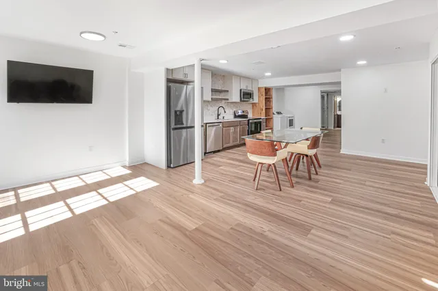 a living room with stainless steel appliances furniture and a flat screen tv