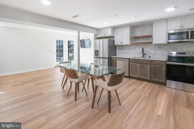 a kitchen with stainless steel appliances granite countertop a stove top oven a sink dishwasher and a dining table with wooden floor