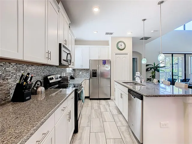 a kitchen with stainless steel appliances granite countertop a sink a stove and refrigerator