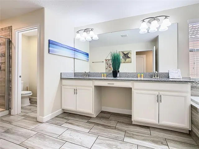 a spacious bathroom with a granite countertop sink a mirror and a toilet