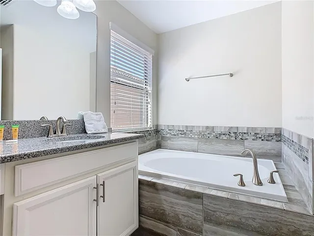 a bathroom with a granite countertop bathtub sink vanity and mirror
