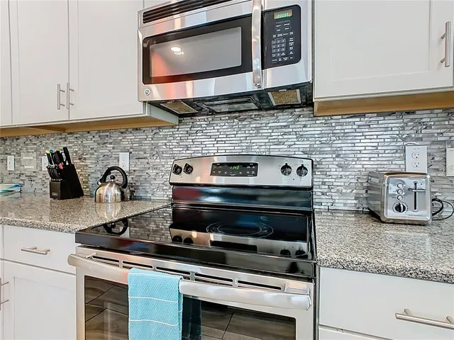 a kitchen with granite countertop stainless steel appliances a stove and a microwave