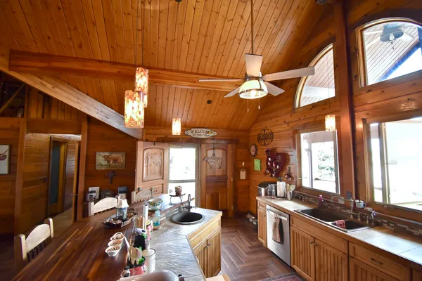 a kitchen with stainless steel appliances kitchen island granite countertop a stove a refrigerator a dining table and chairs with wooden floor