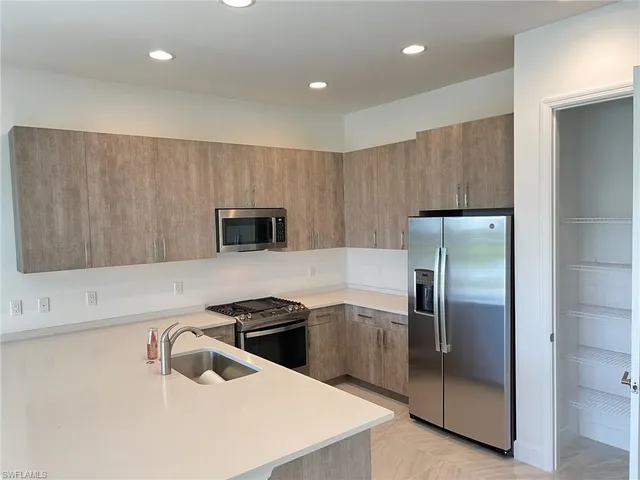 a kitchen with stainless steel appliances granite countertop a refrigerator a sink a stove and a refrigerator with wooden floor