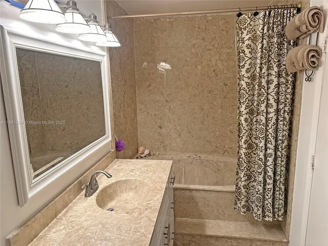 a bathroom with a granite countertop shower and a sink
