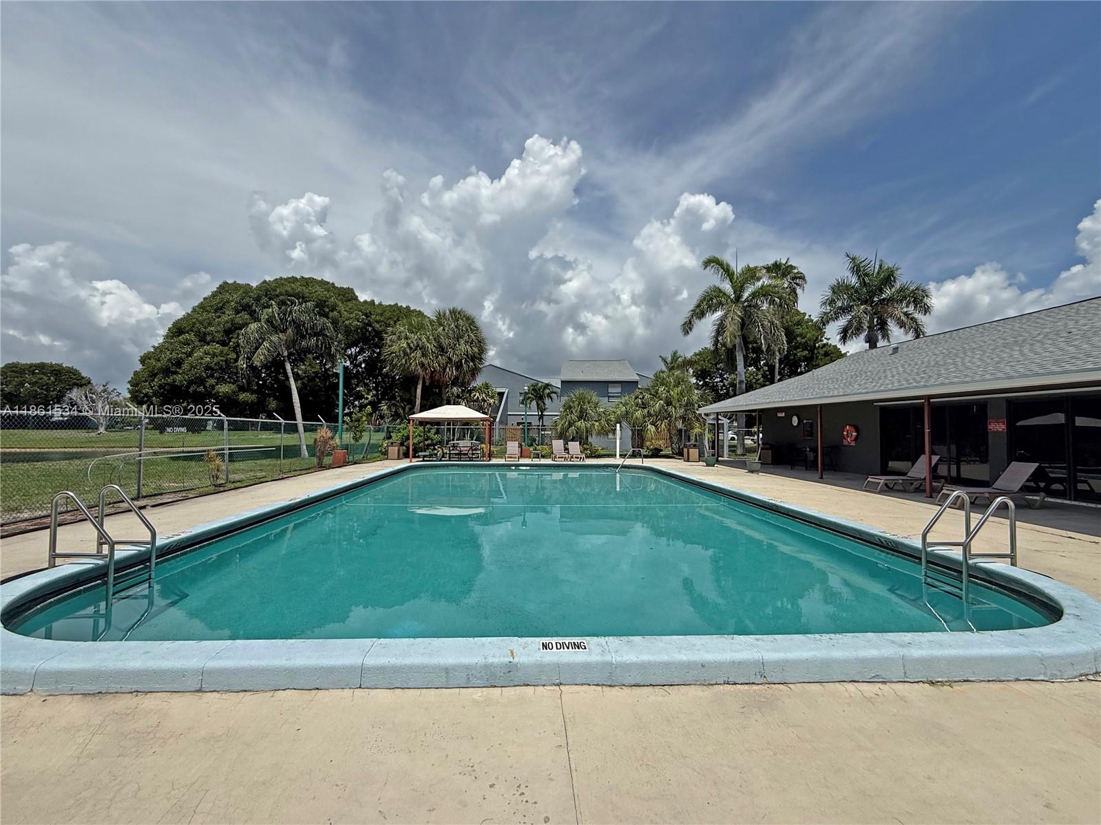 22 Crossings Circle, Unit E Boynton Beach, FL 33435 - Photo 25 of 28 a view of a house with a swimming pool and a yard