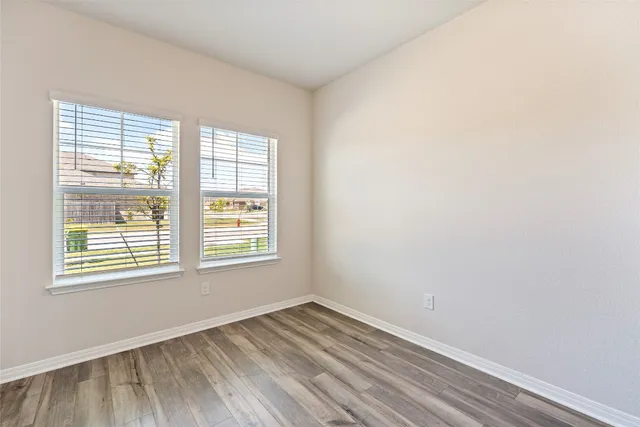 a view of an empty room with wooden floor and a window