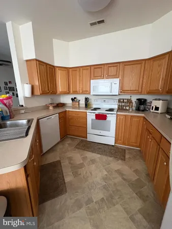 a kitchen with a sink a stove a microwave a refrigerator cabinets and wooden floor