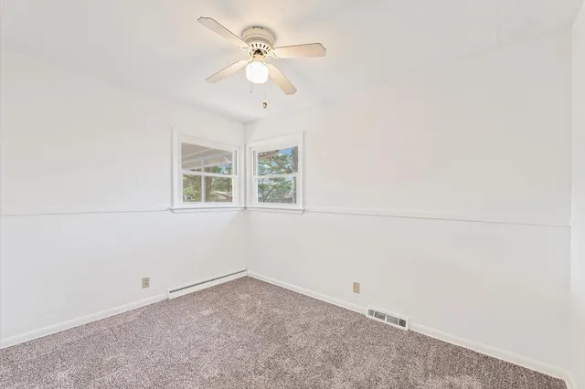 an empty room with a chandelier fan and windows
