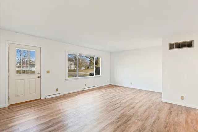 an empty room with wooden floor and window