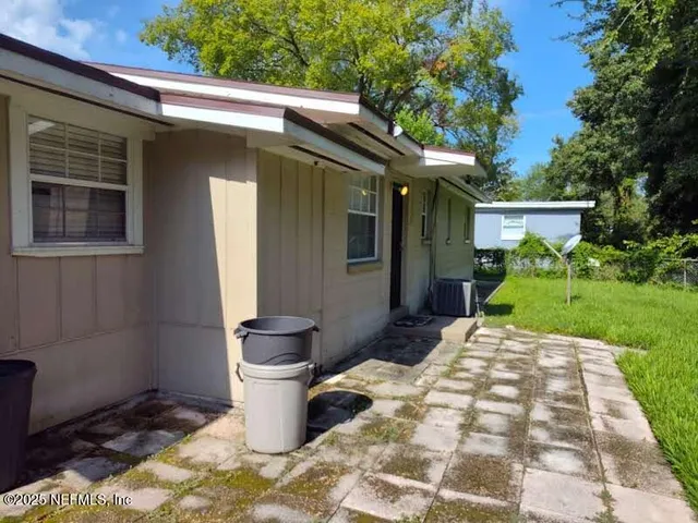 a backyard of a house with fountain plants and large tree