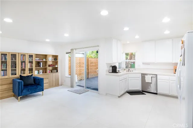 a large white kitchen with kitchen island a sink a stove a refrigerator cabinets and living room view