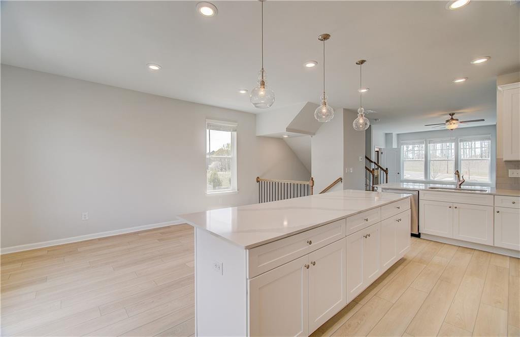 1903 Daybreak Lane Newnan, GA 30265 - Photo 11 of 29 a large white kitchen with a large island oven a sink dishwasher and white cabinets with wooden floor