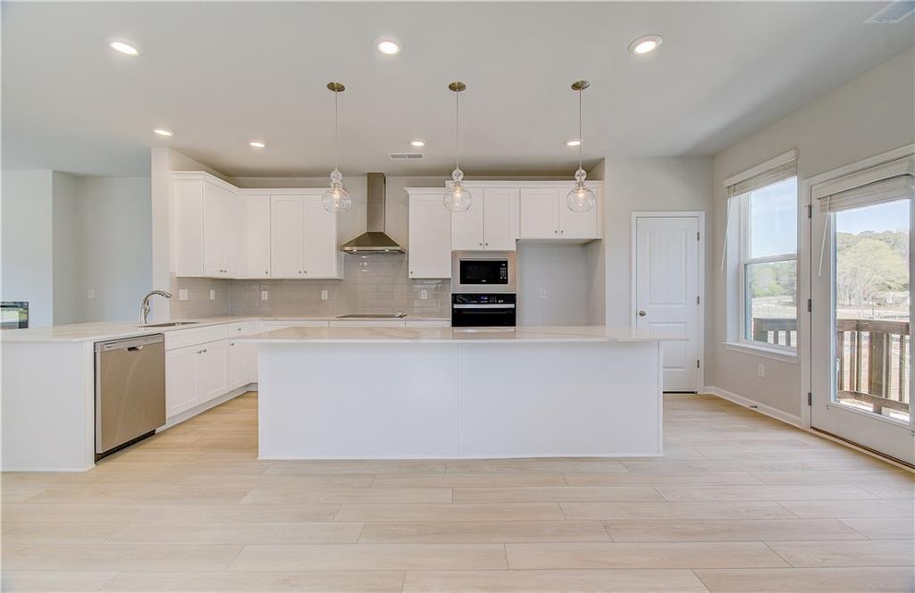 1903 Daybreak Lane Newnan, GA 30265 - Photo 9 of 29 a large white kitchen with kitchen island a sink a center island stainless steel appliances and a window